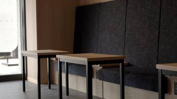 A seating area with two tables and a bench, featuring a combination of wooden and dark fabric surfaces.