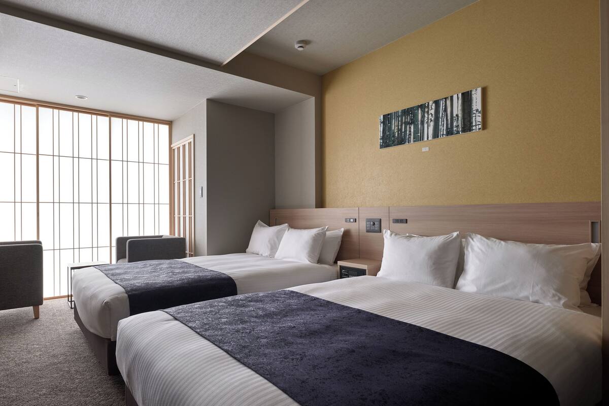 Habitación de hotel con dos camas, un escritorio y una silla.