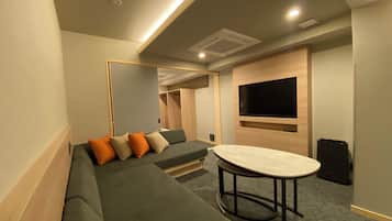 A modern room with a sectional sofa, a round table, a flat-screen TV, and built-in closets.