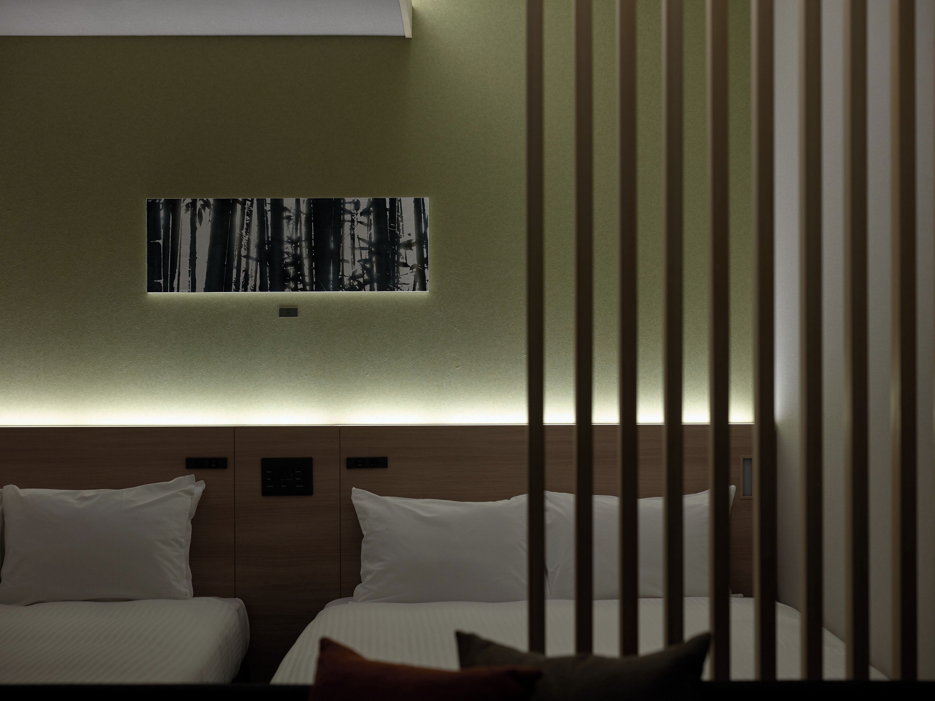 A hotel room with two beds, a wall-mounted artwork of a forest, and a wooden headboard.