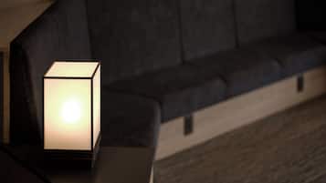 A modern living room with a dark-colored sofa and a small, illuminated table lamp.