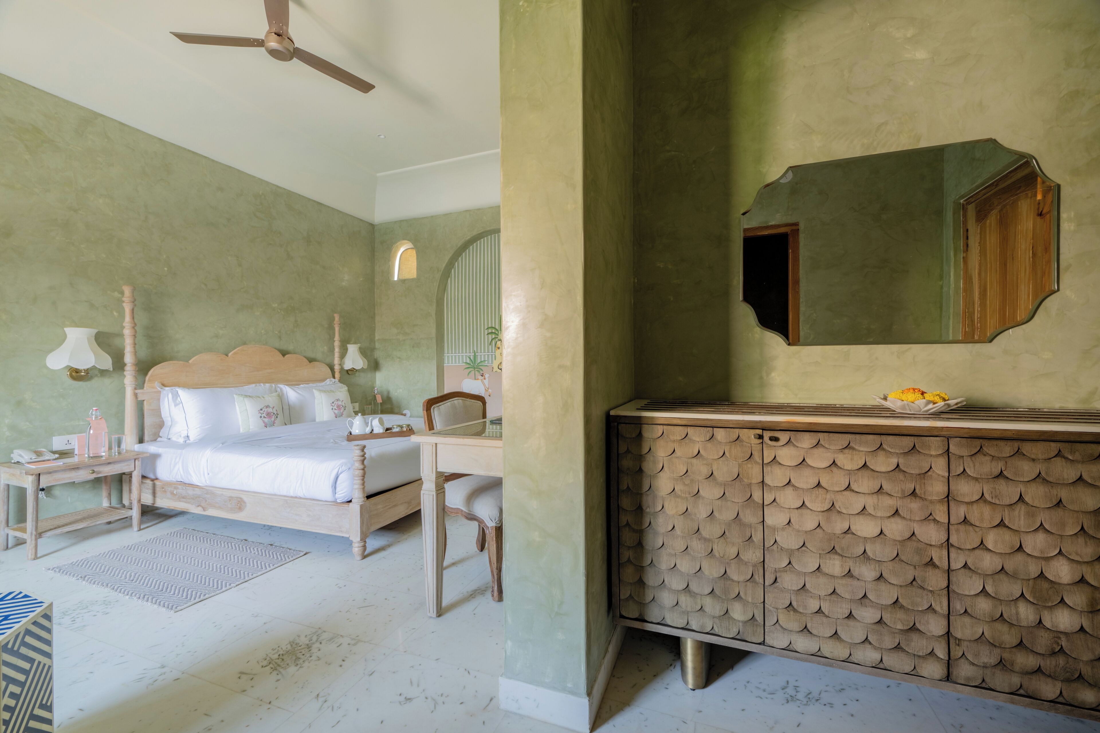 Quarto com cama, mesa de cabeceira e cômoda com espelho.