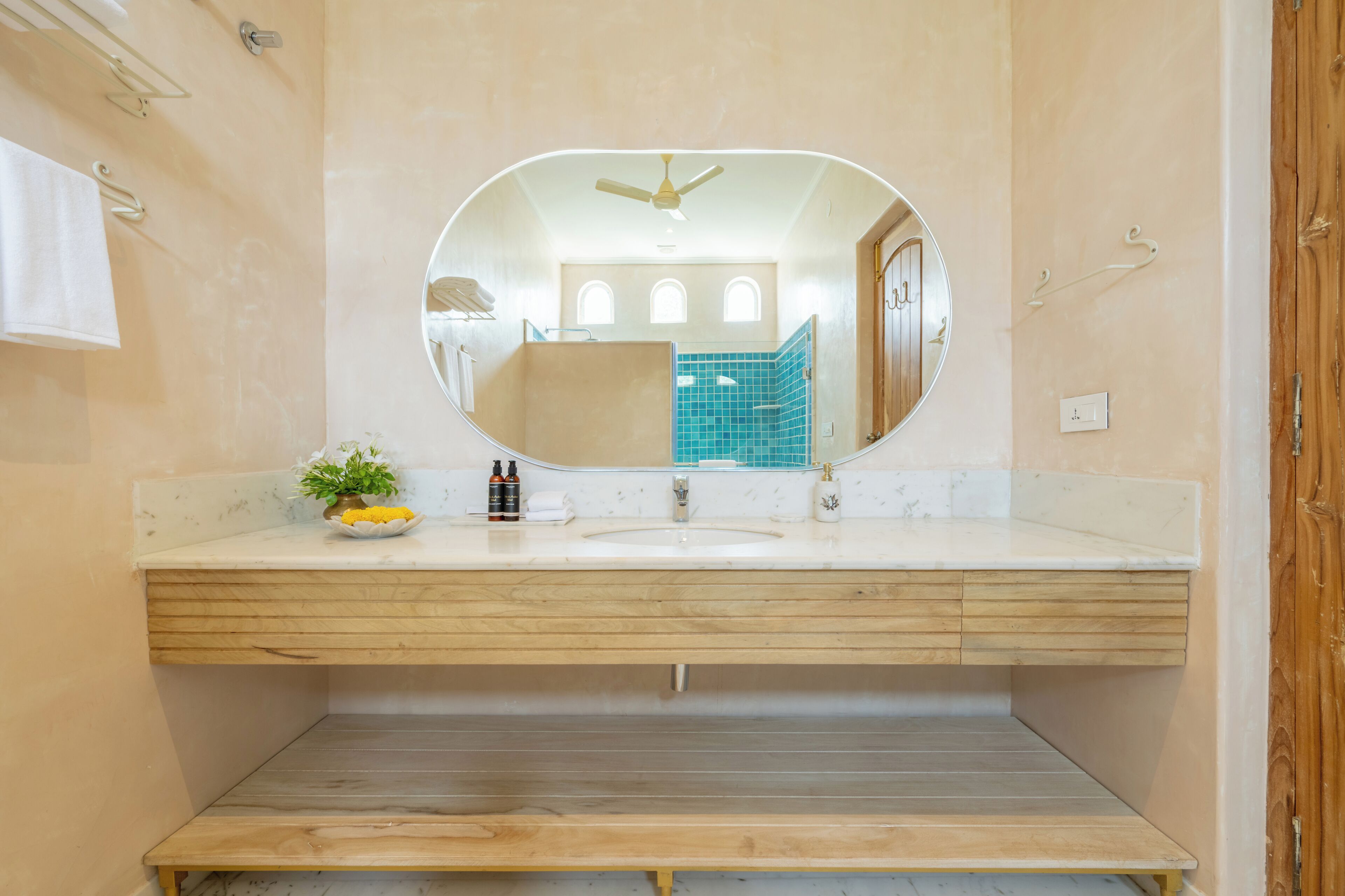 A bathroom with a wooden vanity, a large mirror, and a ceiling fan.