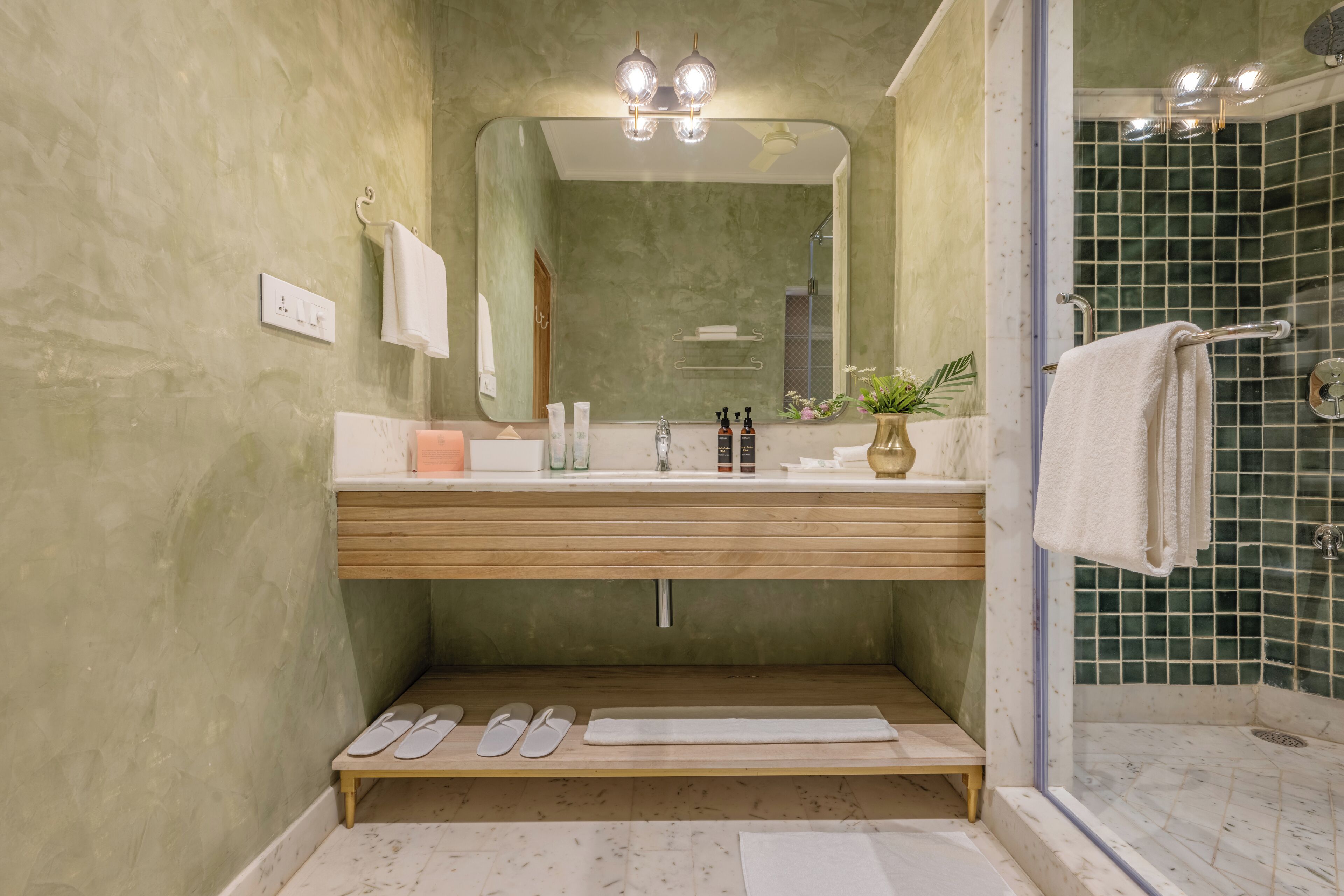 A bathroom with a wooden vanity, a large mirror, a shower with a glass door, and a towel rack.