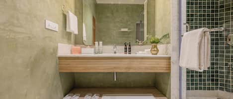 A bathroom with a wooden vanity, a large mirror, a shower with a glass door, and a towel rack.