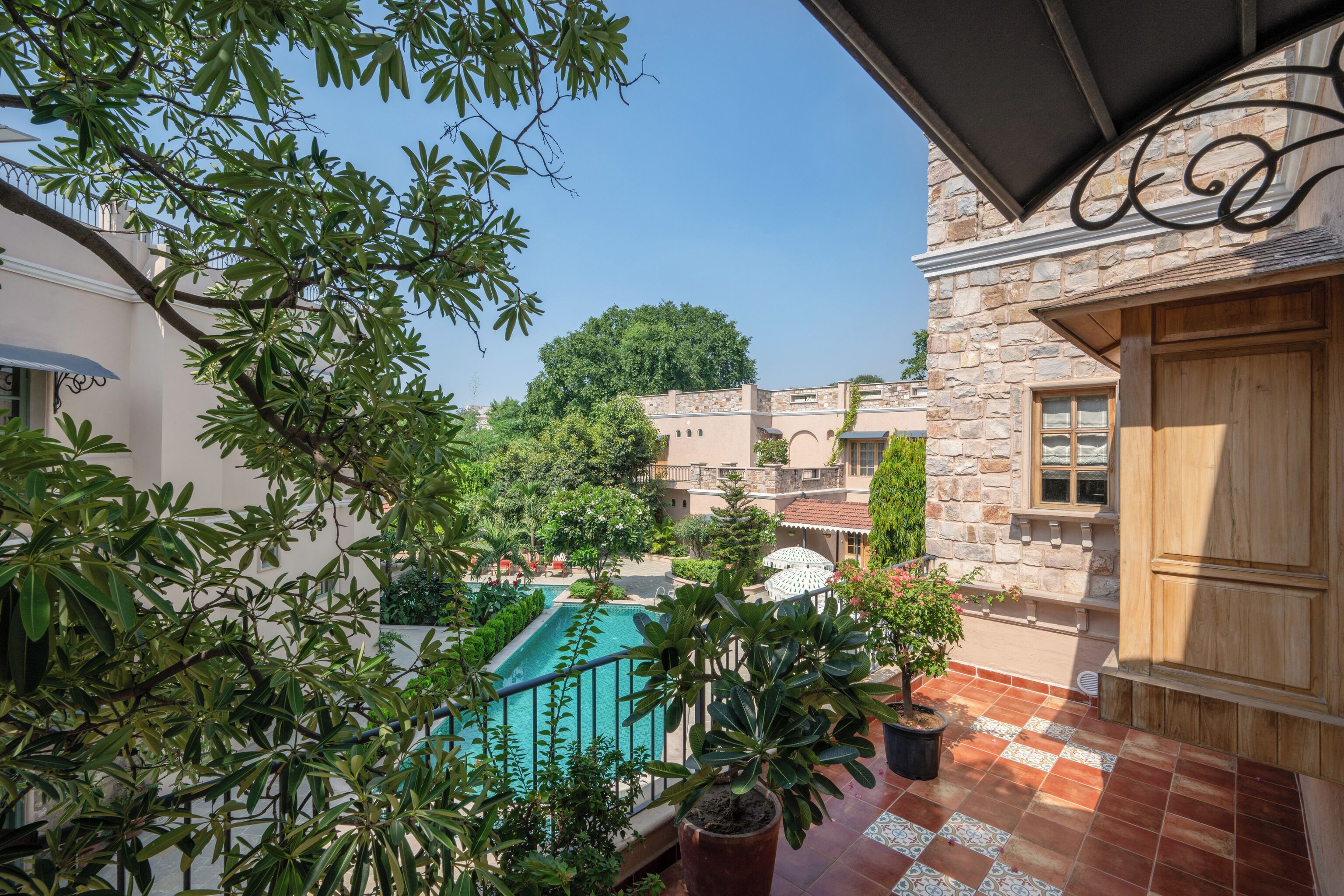 Un patio con piscina, rodeado de edificios de piedra y plantas en macetas.
