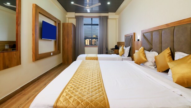A hotel room with two beds, a ceiling fan, a TV, and a window with curtains. - Hotel BKC Minerva  (Mumbai)