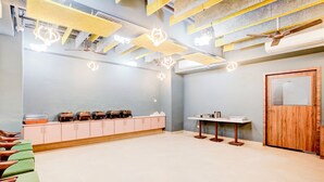A spacious room with a high ceiling, exposed beams, and pendant lighting. There is a wooden door on the right and a table with a mirror on the left. - Hotel BKC Minerva  (Mumbai)