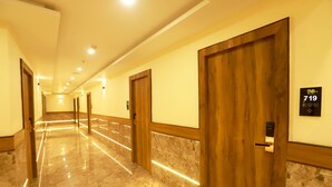 A hotel hallway with marble floors, wooden doors, and illuminated wall sconces. - Hotel BKC Minerva  (Mumbai)