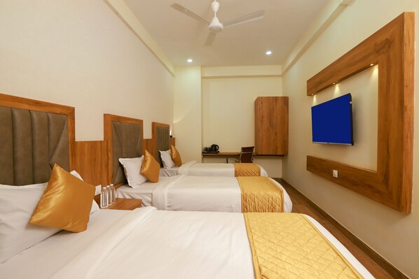 A hotel room with two beds, a ceiling fan, a TV mounted on the wall, and a wooden wardrobe. - Hotel BKC Minerva  (Mumbai)
