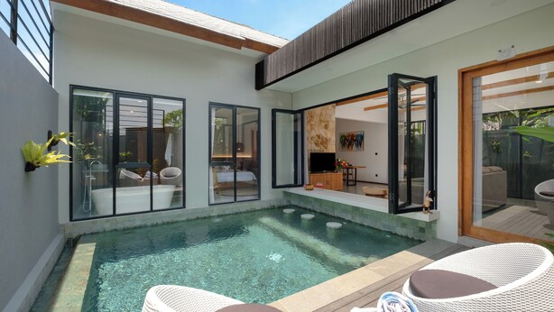 Un espace piscine extérieur moderne, avec une eau cristalline, entouré de portes vitrées donnant accès à un espace de vie.
