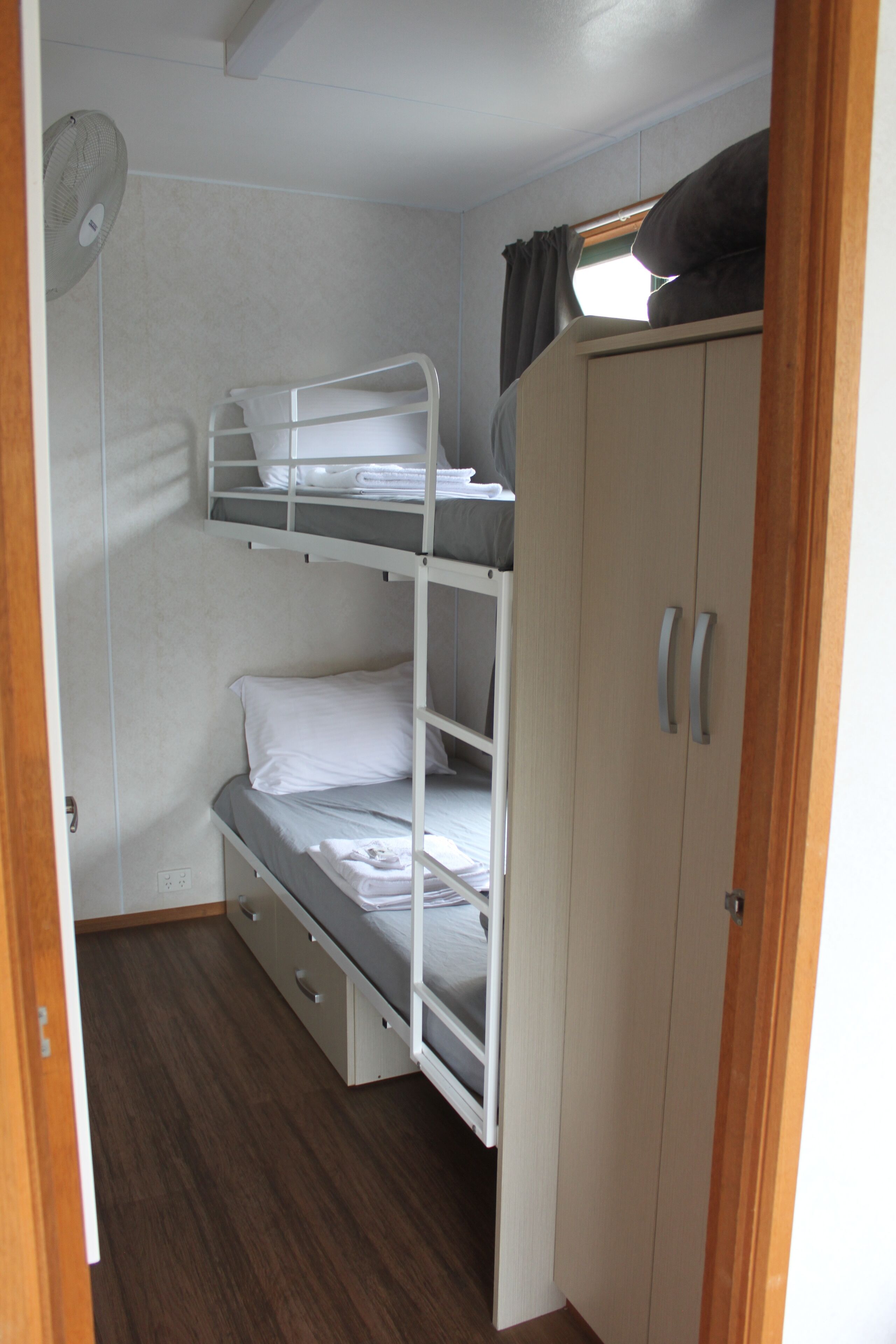 A bunk bed room with a wardrobe and a fan.