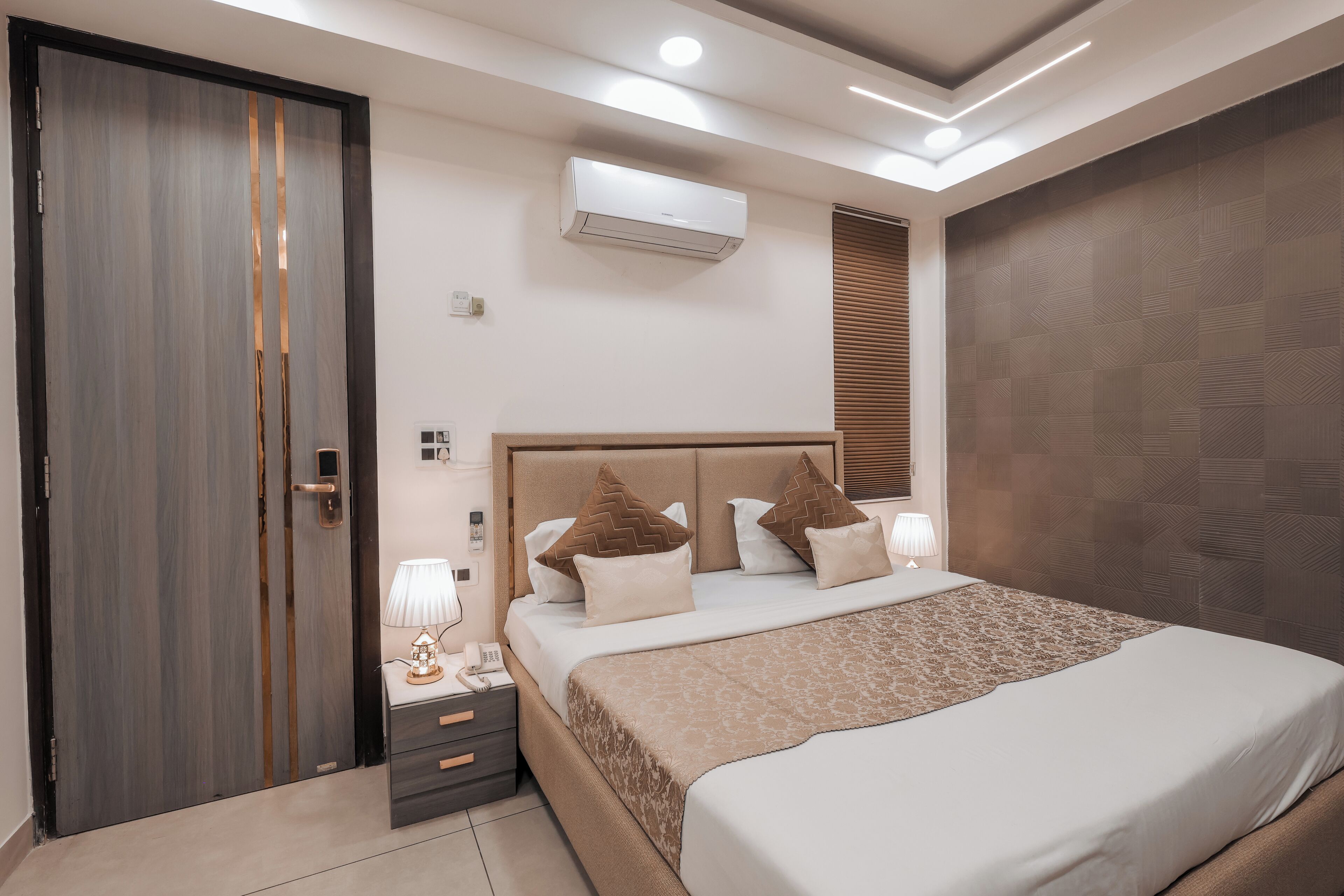 A modern bedroom with a large bed, bedside tables, an air conditioning unit, and a wardrobe.