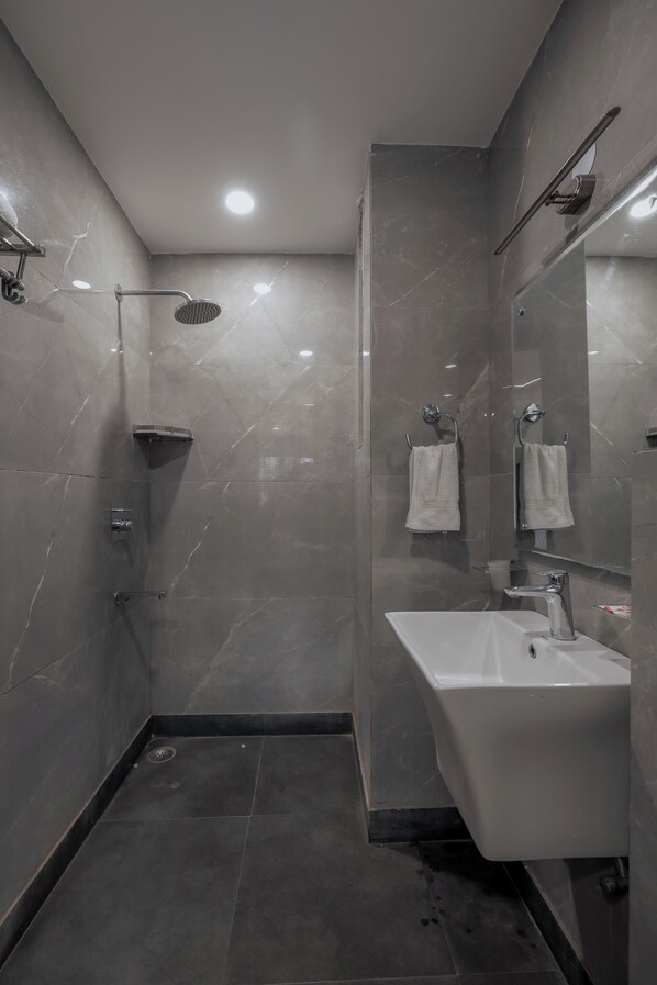 A modern bathroom with a shower, a sink, and a mirror. - Micasa Homes (New Delhi)