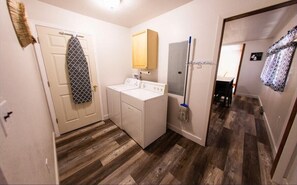 Laundry room with a washing machine and dryer, a towel rack, and a broom.