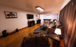 Relax in this stylish living room with a large flat-screen TV, cozy sofa, and pool table.