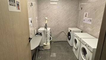A self-service laundry room with a washing machine, dryer, and a hose for washing.