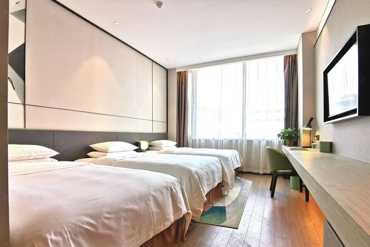 A modern hotel room with two beds, a desk, a chair, and a large window with curtains.