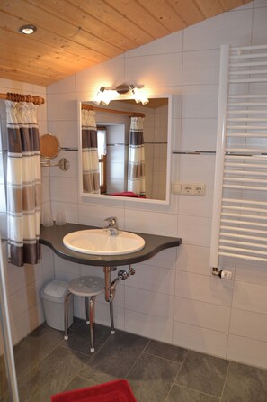 A bathroom with a white sink, a mirror, a towel rack, and a heater.
