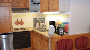 Eine kleine Küche mit Holzschr änken, einem Herd, einer Spüle und einem Toaster.