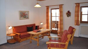 Ein gemütliches Wohnzimmer mit einem Holzsofa, einem Holzstuhl, einem kleinen Tisch und einer Lampe.
