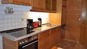 A kitchen with wooden cabinets, a stainless steel sink, a coffee maker, and a clock displaying 11:33. - Apartment 2 - Göllblick, for 1-4 persons, approx. 50 sqm, 1 bedroom, living room/bedroom, kitchen, shower, WC, balcony (Bischofswiesen)