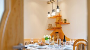 Un coin repas avec une table ronde dressée pour quatre personnes, entourée de chaises en bois dotées de coussins bleus.