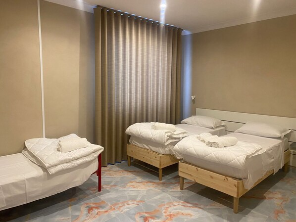 A hotel room with two beds, a wooden floor, and a curtain. - Business house  (Casavatore)