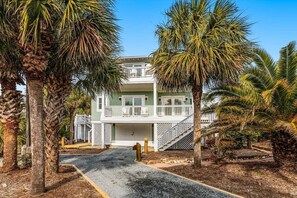 A two-story building with a balcony, surrounded by palm trees.