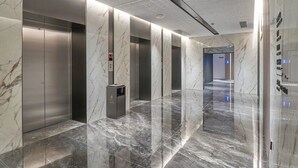 A modern elevator lobby with marble walls and floors, a digital display, and a trash bin. - Lavande Hotel Guangzhou Beijing Road Pedestrian Street Haizhu Square Metro Station Branch - Free Deliver Service to Canton Fair Complex During Canton Fair Period (Guangzhou)