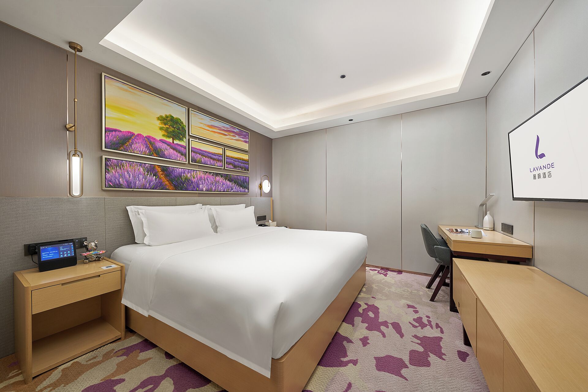 A hotel room with a bed, bedside tables, a desk, a chair, a flat-screen TV, and a ceiling light.