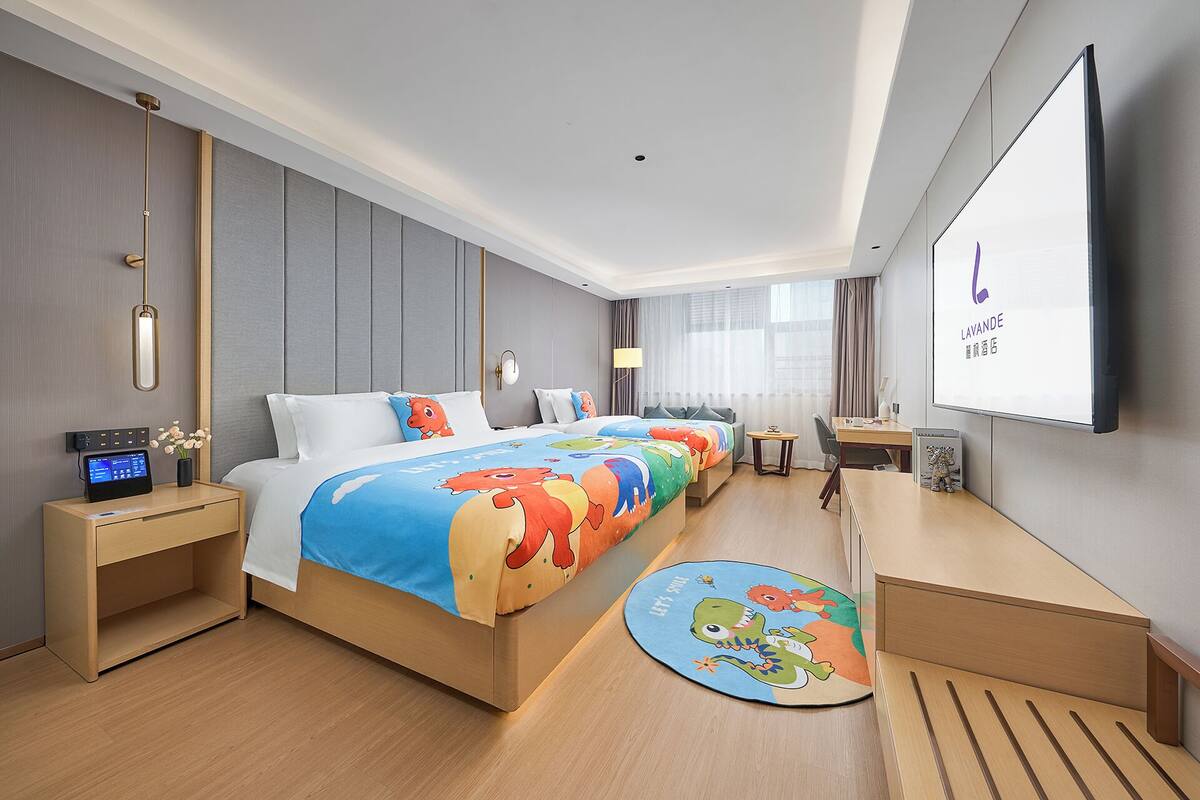 A hotel room with a large bed, bedside tables, a desk, and a TV screen.