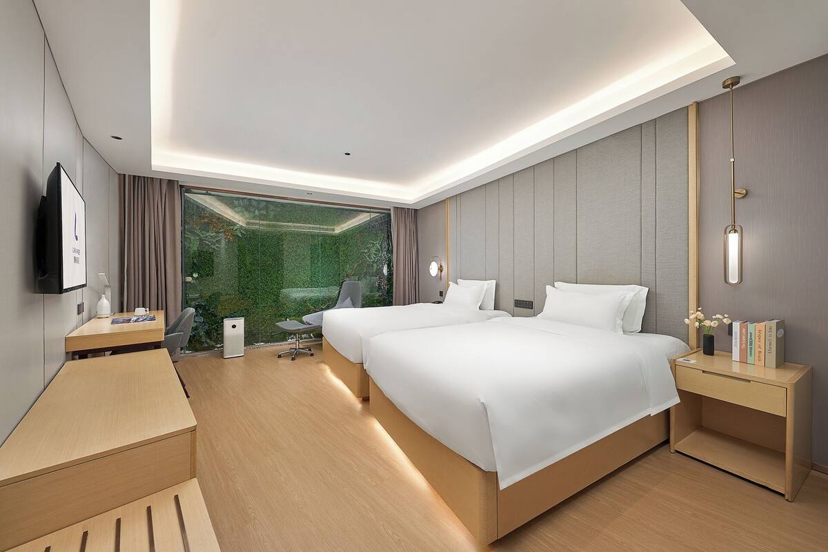 A modern hotel room with a large bed, bedside tables, a desk, and a TV.
