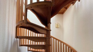Un escalier en colimaçon en bois, doté d’une main courante et d’un palier.