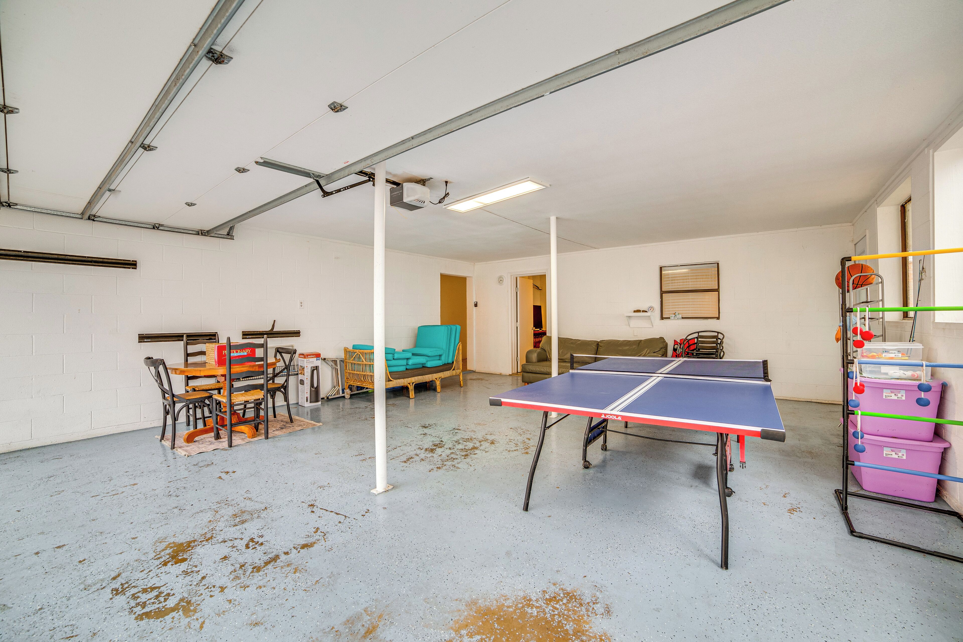 Una habitación amplia con mesa de ping pong, una mesa de comedor con sillas y un sofá.