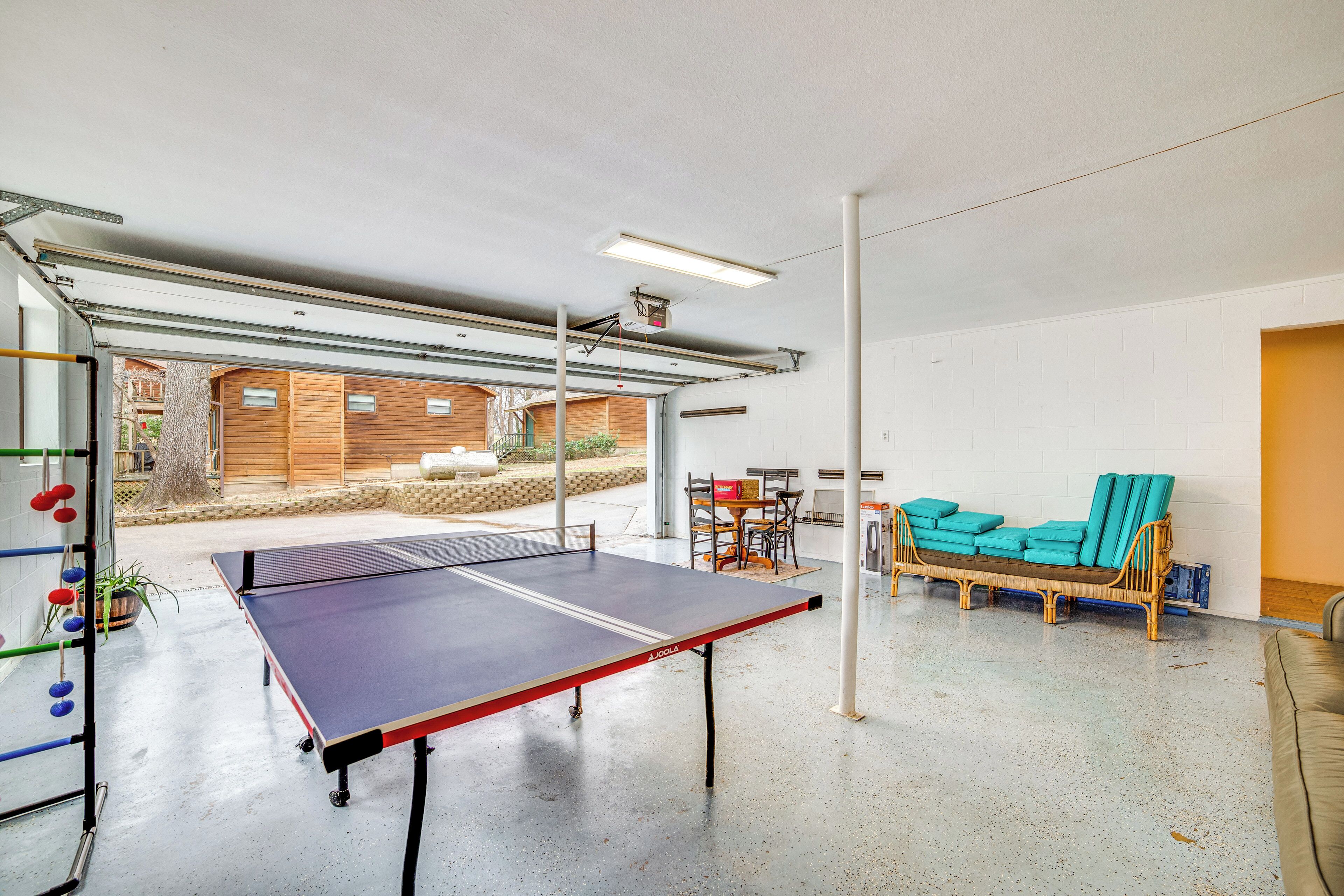 Et ping pong-bord i et rummeligt lokale med betongulv, et træbord og en fletsofa.