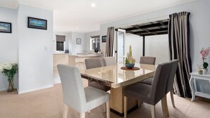 Un comedor moderno con una mesa de vidrio, sillas tapizadas en gris y una pequeña planta en maceta.