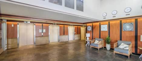 A spacious lobby with a high ceiling, wooden paneling, and a large open area with a patterned rug.