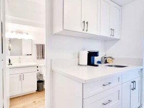 A modern kitchen with white cabinetry, a built-in oven, and a sink.