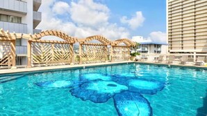 A swimming pool with a floral design, wooden pergolas, and a view of a hotel building. - 23 FL-Cozy & Elegant King Studio (Honolulu)