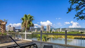 A balcony with two lounge chairs overlooking a body of water and cityscape. - 23 FL-Cozy & Elegant King Studio (Honolulu)