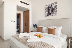 A modern hotel room with a large bed, a bedside table with a tray of breakfast, a painting on the wall, and a closet. - Binghatti Onyx - 1413 1BD (Dubai)