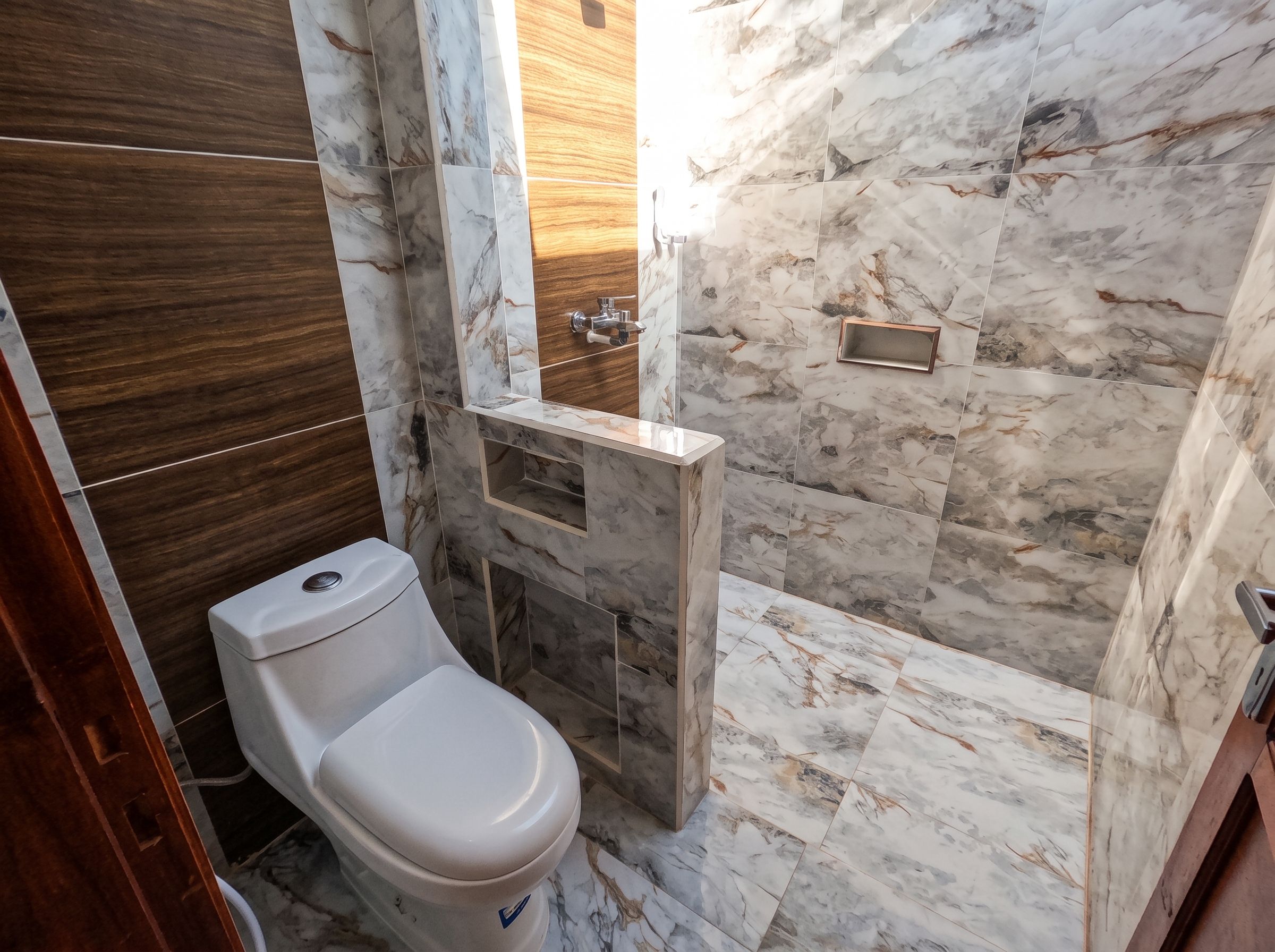 Un baño con inodoro, zona de ducha y tocador con espejo.