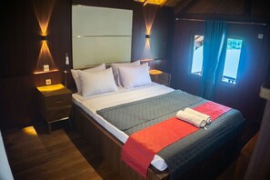 Un lit simple avec une couverture rouge et bleue, une tête de lit en bois et des lampes de chevet.