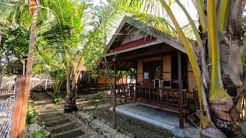 A wooden structure with a porch, surrounded by tropical vegetation.