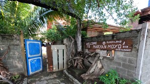 A rustic entrance with a wooden gate, a stone pathway, and a sign welcoming to Maryan Moyo Bar & Restaurant. - Maryan Moyo Bungalows and resto (Moyo)