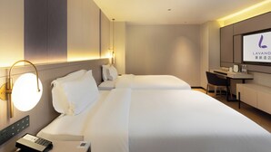 Una habitación de hotel con una cama grande, un escritorio y un televisor mostrando el nombre del hotel.