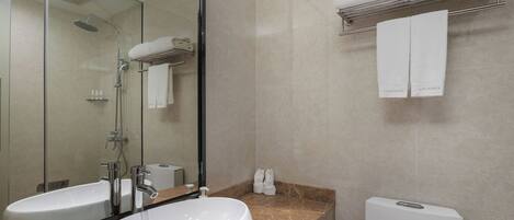 A modern bathroom with a large mirror, two sinks, a shower, and a toilet.