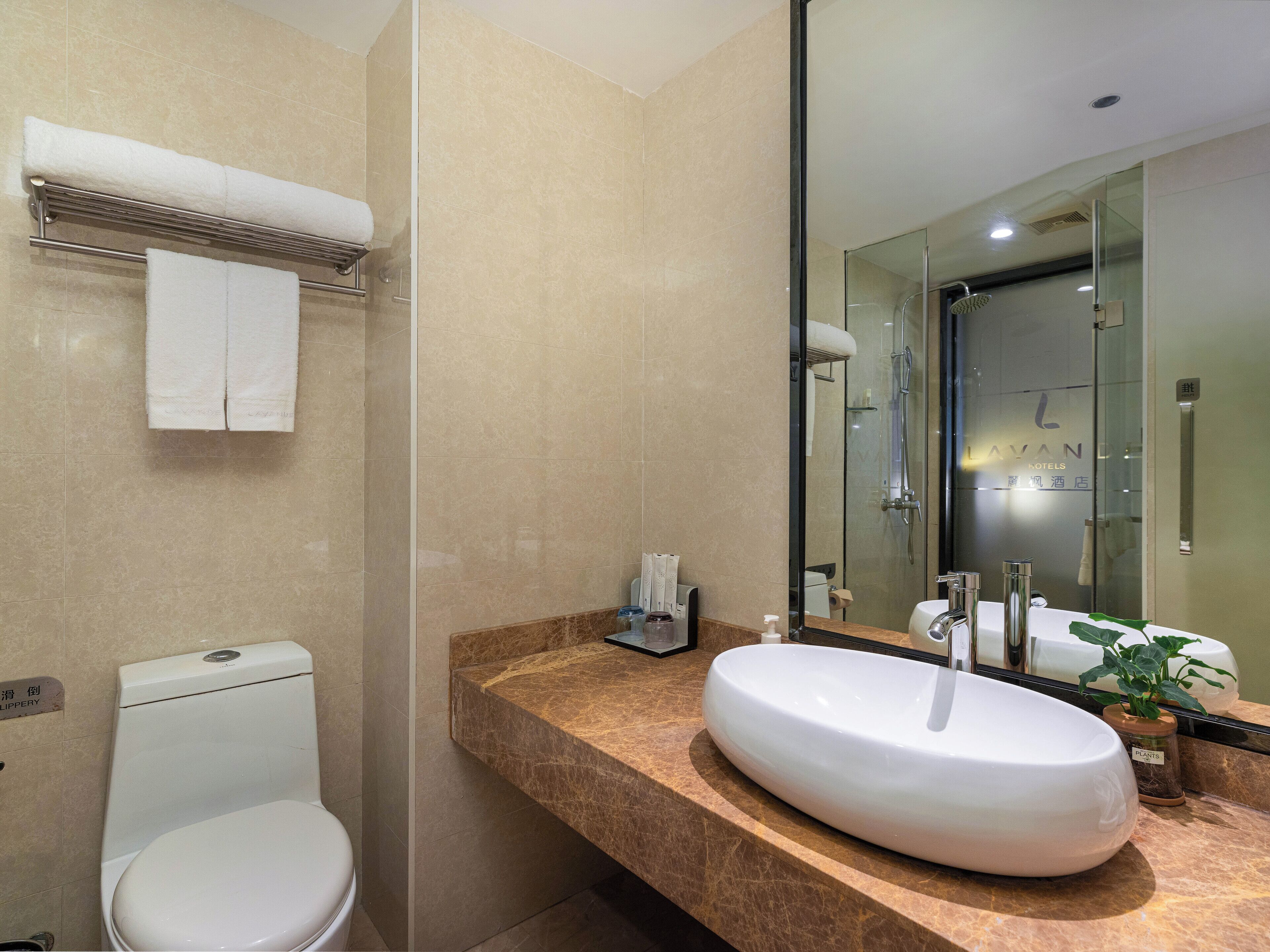 A modern bathroom with a white toilet, a large sink with a marble countertop, and a glass shower enclosure.