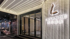 Fachada de hotel con diseño moderno, que presenta una puerta de cristal y un revestimiento de mármol.